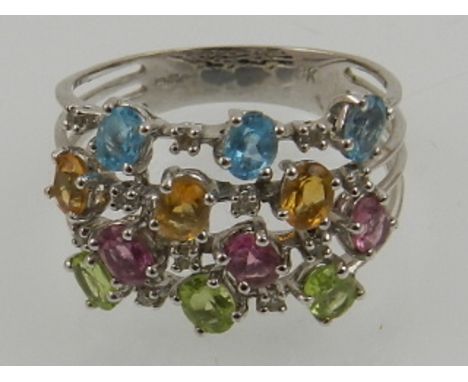 A 9 carat white gold, blue topaz, citrine, pink sapphire, and peridot four banded ring, the stones interspersed with diamond 