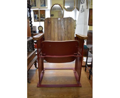 A vintage red painted metal and ash folding cinema seat. 