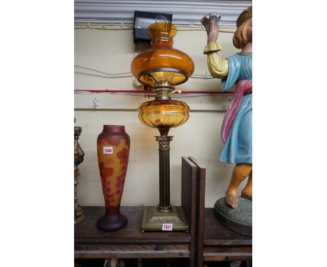 A brass Corinthian column oil lamp,&nbsp;with amber glass reservoir and shade, height excluding chimney 70cm.&nbsp; 