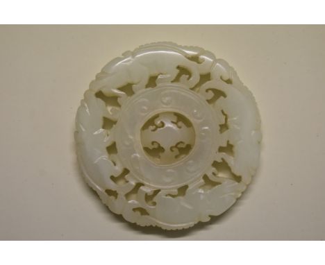 A Chinese carved and pierced pale celadon jade roundel,&nbsp;the rim carved with lingxhi dragons, with rotating centre, 5.5cm