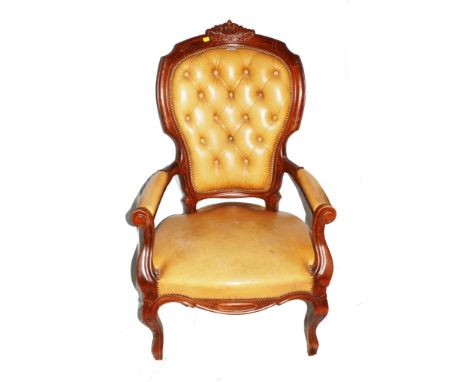 A Victorian-style mahogany framed leather upholstered armchair with profuse carving to the top rail, button back support, lea
