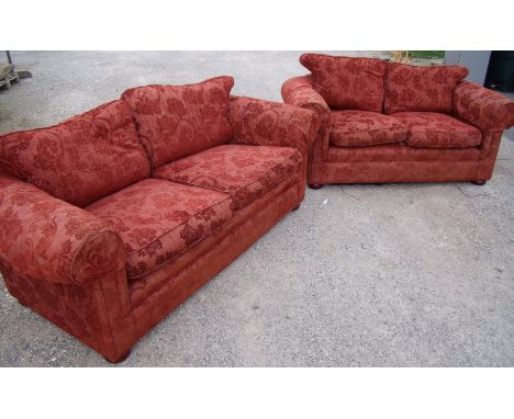 Modern two piece suite in red upholstery comprising of a large two seat sofa and smaller two seat sofa on raised bun supports