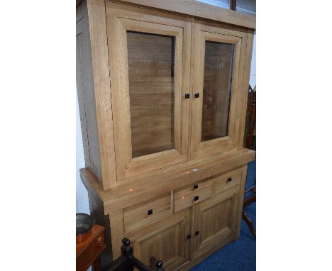 A LIGHT OAK GLAZED TWO DOOR BOOKCASE, with four various drawers above double cupboard doors, approximate size width 133cm x h