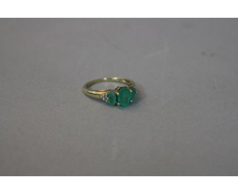 A 9CT THREE STONE EMERALD RING, with diamond shanks, ring size K, approximate weight 2.0 grams