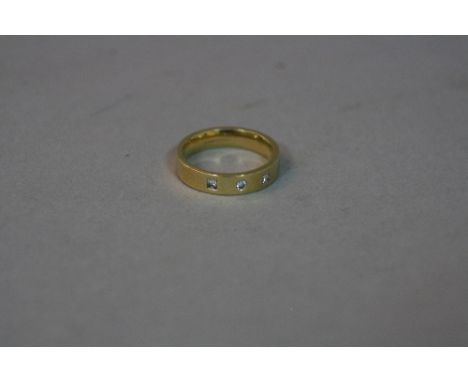 A MODERN DIAMOND 18CT GOLD RING, a plain polished yellow gold band ring set with a modern round brilliant cut diamond and two