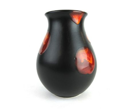 A Poole Pottery vase of squat form, the black ground decorated with a red glaze, h. 16 cm