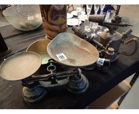 Two brass blowlamps with two brass metal handled sauce pans and a set of balance scales