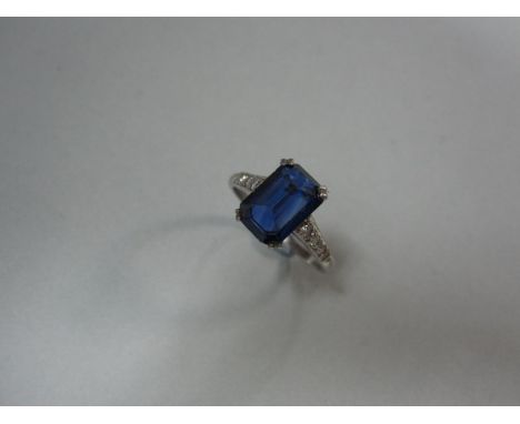 An Art Deco sapphire and diamond ring, the octagonal cut sapphire four double-claw set pavilion up, each shoulder with a line