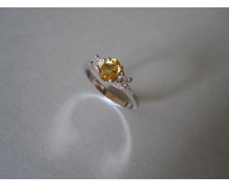 A yellow sapphire and diamond three stone ring set in 18ct gold, the oval cut deep yellow sapphire four claw set between roun