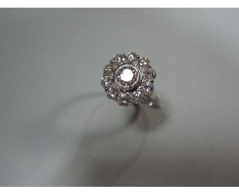 A diamond flower head cluster ring, the central round brilliant cut diamond collet set in a border of ten smaller similar dia