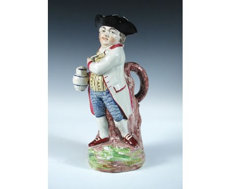 An early 19th century Hearty Good Fellow Toby jug, he stands by a tree trunk a branch of which forms the handle, a pipe in hi