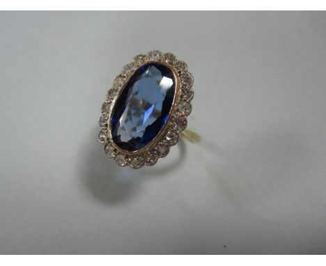 A blue hardstone and diamond cluster ring, the central oval cut stone is a sapphire, possibly synthetic or a doublet, collet 