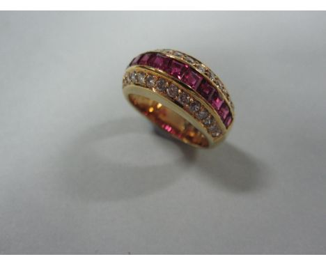 A ruby and diamond band ring, the front raised in a slight arch and set with a line of calibré cut rubies between lines of ro