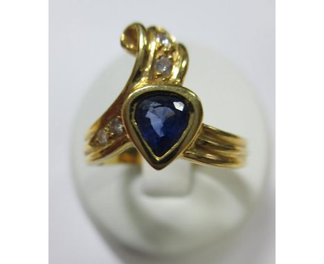 An 18ct gold asymmetric tanzanite and diamond ring, the reeded ribbon band terminating at one end with a collet set pear cut 