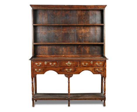 A small Regency oak dresser, with raised boarded plate rack and fitted three small drawers, further false drawers, with brass