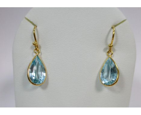 A pair of 18ct gold and blue topaz drop earrings, each wire hook suspending a spectacle set pear cut light blue topaz, laser 