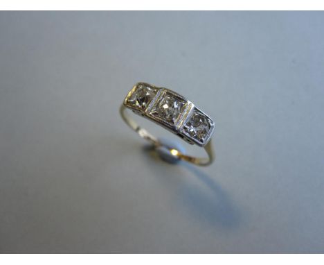 An art deco three stone diamond ring, the graduated old cut diamonds, two cushion one round, in millegrain squared settings o