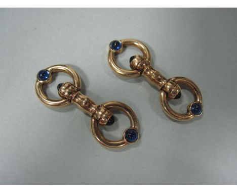 A pair of cufflinks set with cabochon sapphires, of snaffle-bit form, double ended with sprung hinged hoops set with circular