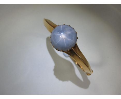 A star sapphire hinged bangle, the 1.8cm diameter cabochon pale blue-grey sapphire displaying strong asterism, multi claw set