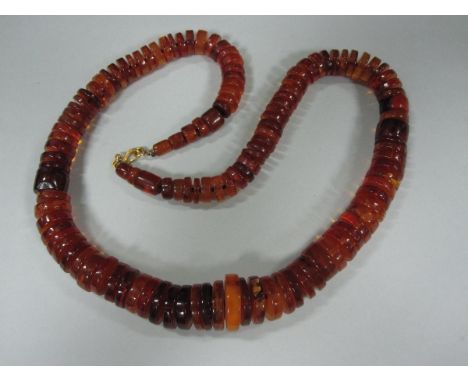 An amber bead necklace, composed of graduated discs of varying thickness, colour and opacity, many with inclusions, S-hook an
