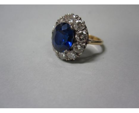 A diamond and synthetic sapphire cluster ring, the oval cut royal blue sapphire of synthetic origin four claw set above a bor