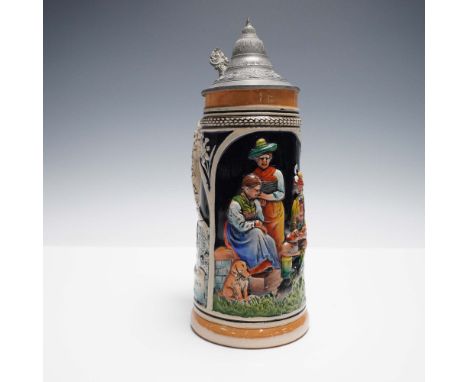 Traditional German beer stein featuring a detailed hand-painted relief scene of a family gathering in a pastoral setting. The