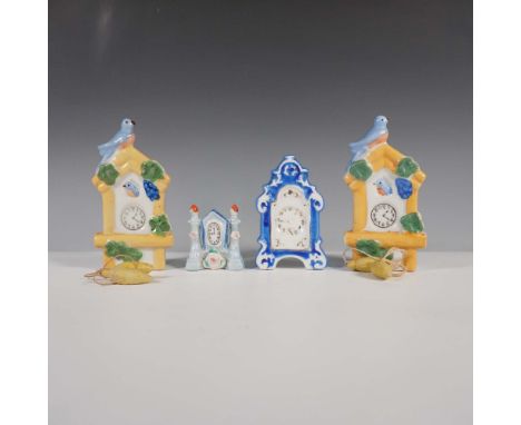 A charming collection of four vintage miniature porcelain clocks, each showcasing intricate hand-painted details and delicate