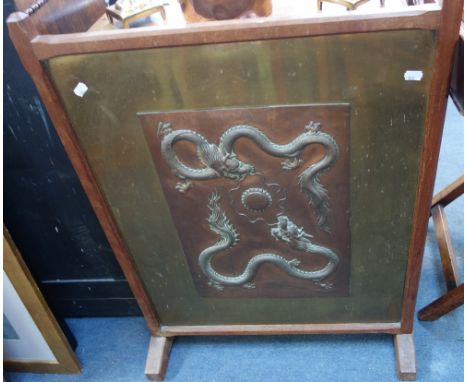 A CHINESE REPOUSSE COPPER PANEL depicting two dragons chasing a flaming pearl, mounted as a fire screen