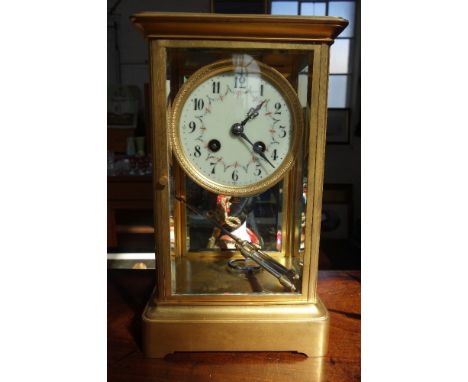 AN EDWARDIAN GILT BRASS FOUR GLASS CLOCK with compensated mercury pendulum striking on a gong, 27cm high