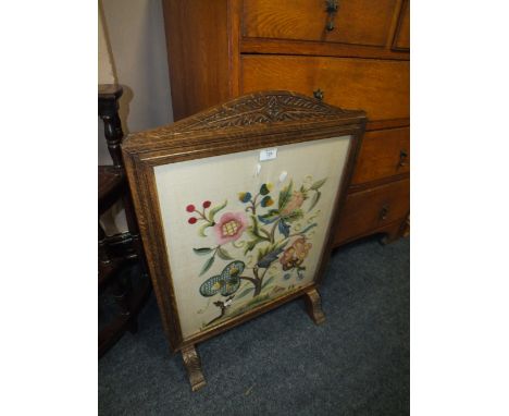 A CARVED OAK GLAZED FIRESCREEN WITH NEEDLEWORK DETAIL