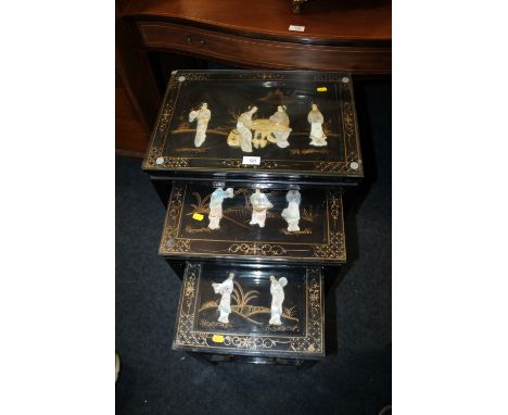 AN ORIENTAL GLASS TOPPED PAINTED NEST OF TABLES WITH MOTHER OF PEARL FIGURATIVE DETAIL