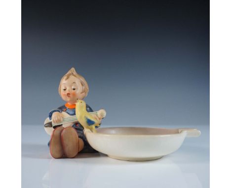 This Goebel Hummel ashtray, titled Joyful, features a charming hand-painted scene of a young child joyfully playing a mandoli