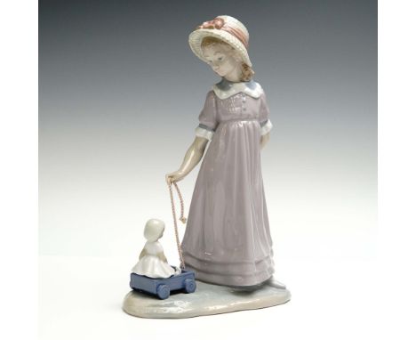 Girl with Toy Wagon (01005044) by Lladro is a sweet and nostalgic figurine sculpted by Vincente Martinez, capturing a quiet c