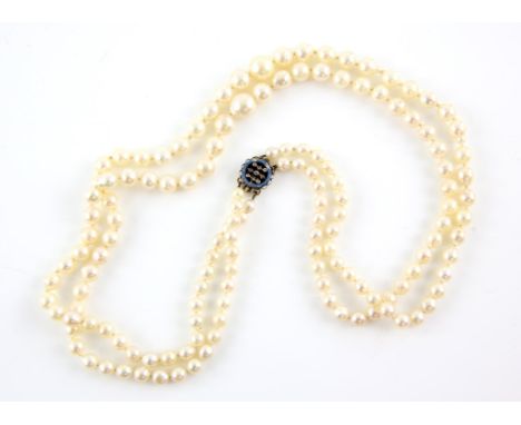 An Edwardian two row pearl necklace, two graduated rows of cream pearls, measuring from 4.7-9.5mm, strung knotted, on an blue
