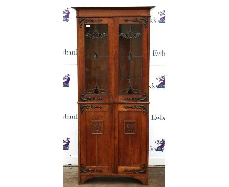 Late Victorian Art Nouveau style bookcase cabinet, with brass hinges, lead glazed doors over a pair of carved doors on bracke