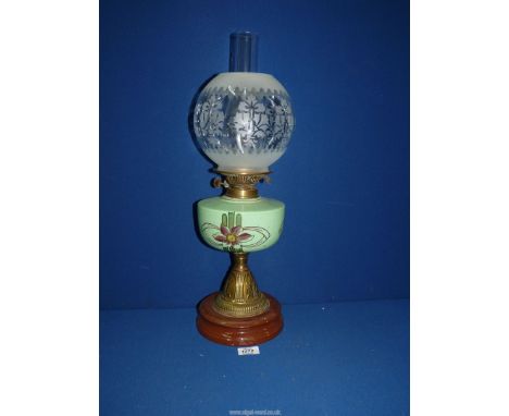 An oil lamp with ceramic base, brass column, green ceramic reservoir with floral decoration and etched glass shade with chimn