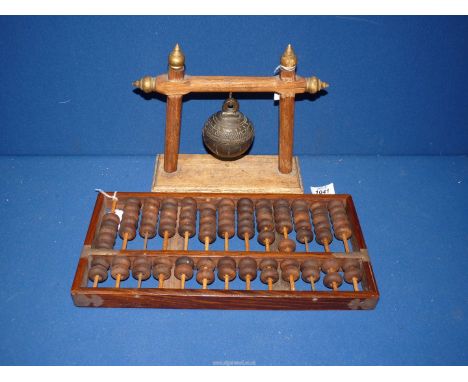 A bronze Crotal bell of some age on a frame, 9" long, plus a mahogany frame Abacus mounted in brass, 14" x 7".