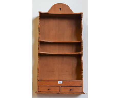 A 19th century pine concave fronted spoon rack, shaped cresting above two rows of apertures, a shelf and a niche, the base wi