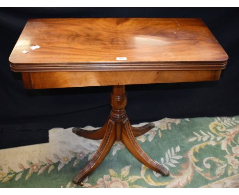 A 20th century mahogany card table, hinged top enclosing a baize lined playing surface, turned column, reeded sabre legs, lio