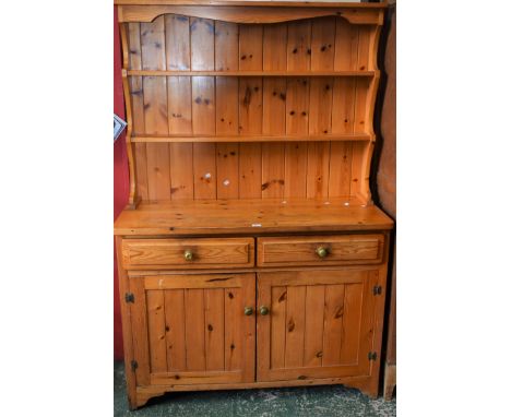 A 20th century pine kitchen dresser, plate racks above two short drawers and a pair of cupboard doors enclosing a shelf, 122c