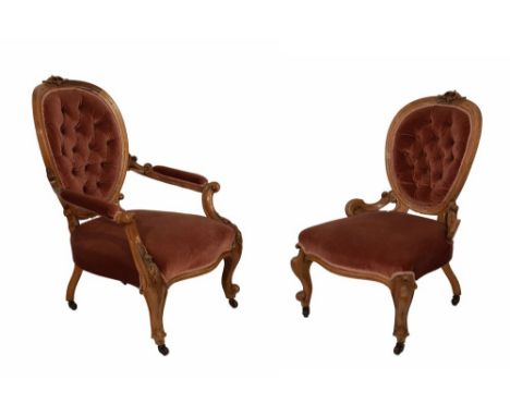 Pair of Victorian walnut button back salon chairs, for a lady and gentleman, the latter with padded arms, each with oval back