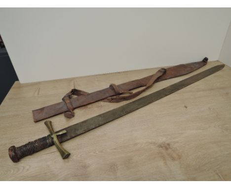 A Sudanese Kaskara Sword having highly decorated blade with Arabic script, wooden grip with leather binding, brass cruciform 