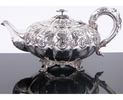 An ornate 19th century silver teapot,
possibly Scottish, with relief decorated acanthus scrolls allover and lion paw feet, st