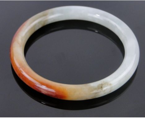 A Chinese polished coloured jade bangle,
inside diameter 54mm.