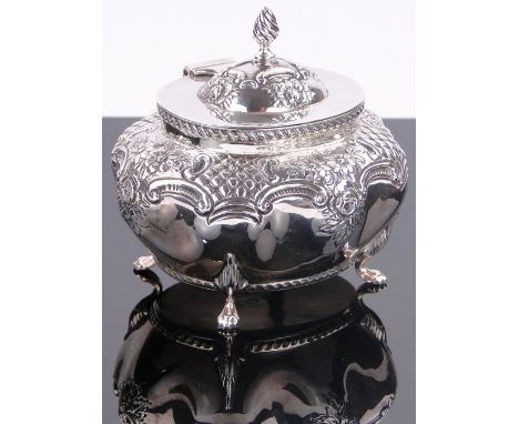 An Edwardian silver tea caddy of bulbous oval form,
with relief decorated shoulders and lion paw feet, makers marks T H, Birm
