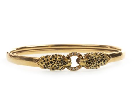 GOLD ENAMELLED PANTHER MOTIF BANGLE, the terminals modelled as panthers heads with enamelled decoration grasping a diamond se