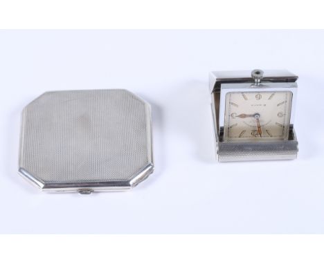 An engine turned silver cased travelling alarm clock and an engine turned compact