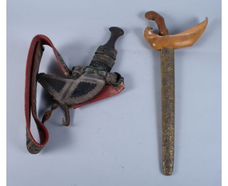 A mid 20th century kris with brass scroll scabbard and a silver mounted jambiya with leather scabbard and belt