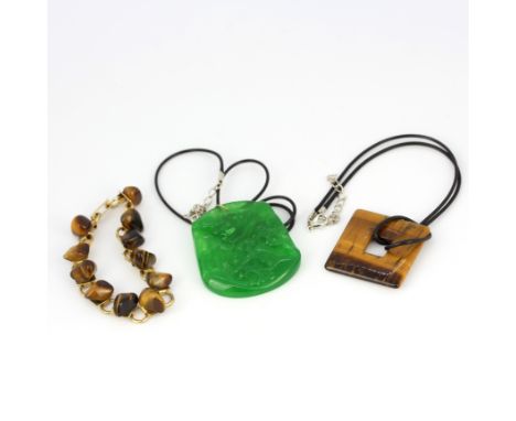 A Chinese carved apple green jade amulet necklace of a mountain scene together with a large tigers eye amulet neckalce and a 