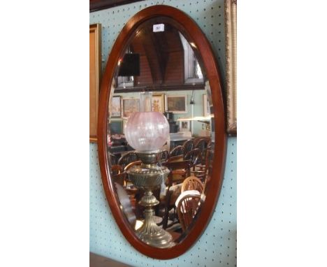 An Edwardian mahogany framed oval wall mirror, with bevelled plate.